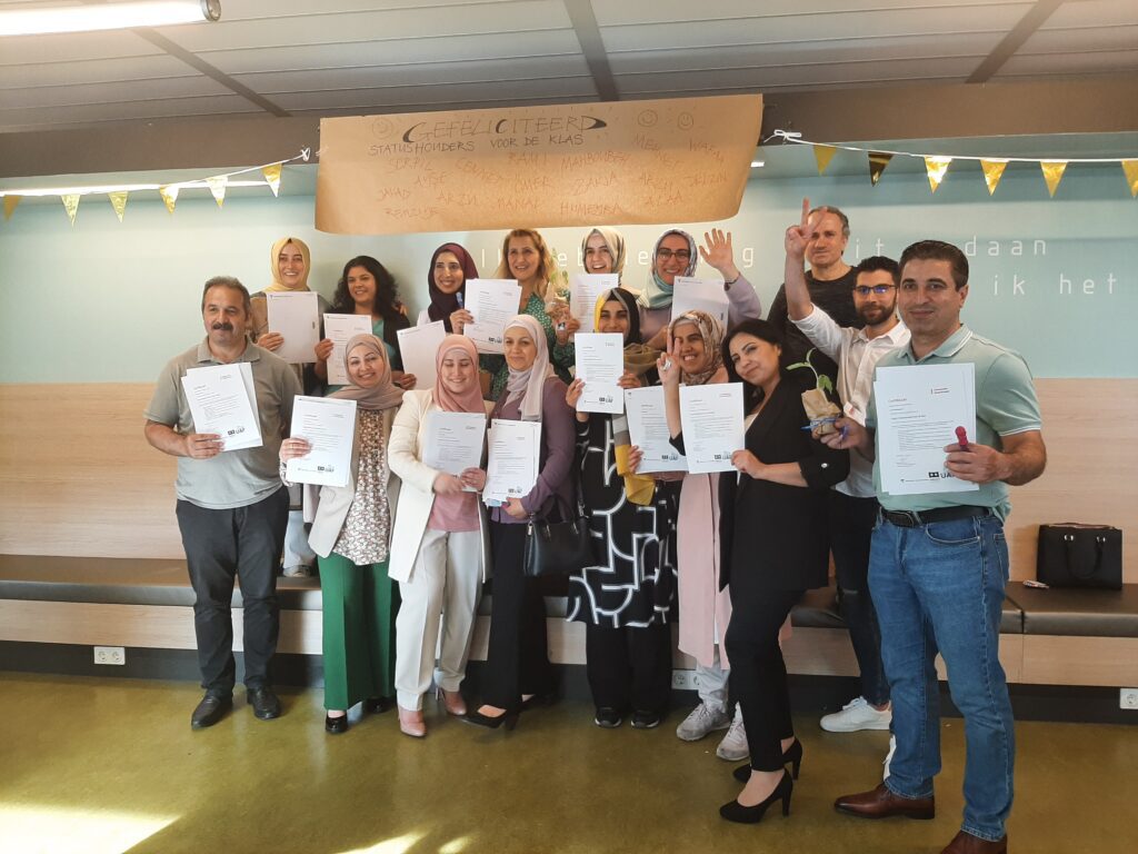 Enthousiaste groep deelnemers Statushouders voor de Klas Amsterdam met hun diploma